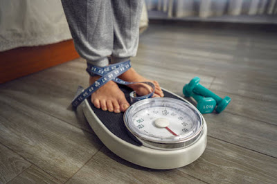 How to Manage Your Caloric Intake for Fitness Progress Close up of feet standing on weight scale. High resolution 42Mp indoors digital capture taken with SONY A7rII and Zeiss Batis 25mm F2.0 lens